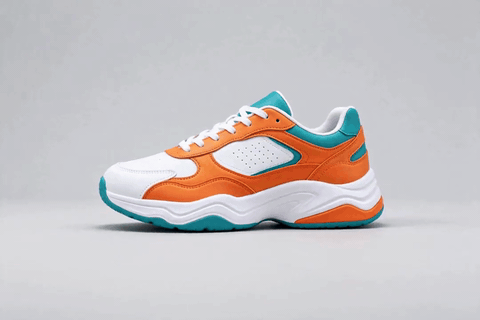 An orange and teal sneaker turning on a plain floor, as a looping GIF