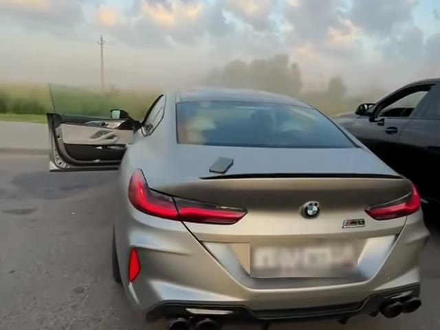 Two parked cars at the gas station, one with its door open, where the third beat begins